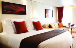 Celebrity Silhouette - Celebrity Cruises - postel, stolek s vychlazenou láhví šampaňského a dekorativní obrazy v suite kajutách