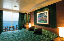 MSC Musica - MSC Cruises - luxusní kajuta se zeleným potahem na posteli, soukromým balkónem a uměleckým obrazem nad postelí.