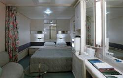 Rhapsody of the Seas - Royal Caribbean International - manželská postel a bílý nábytek v kajutě na lodi